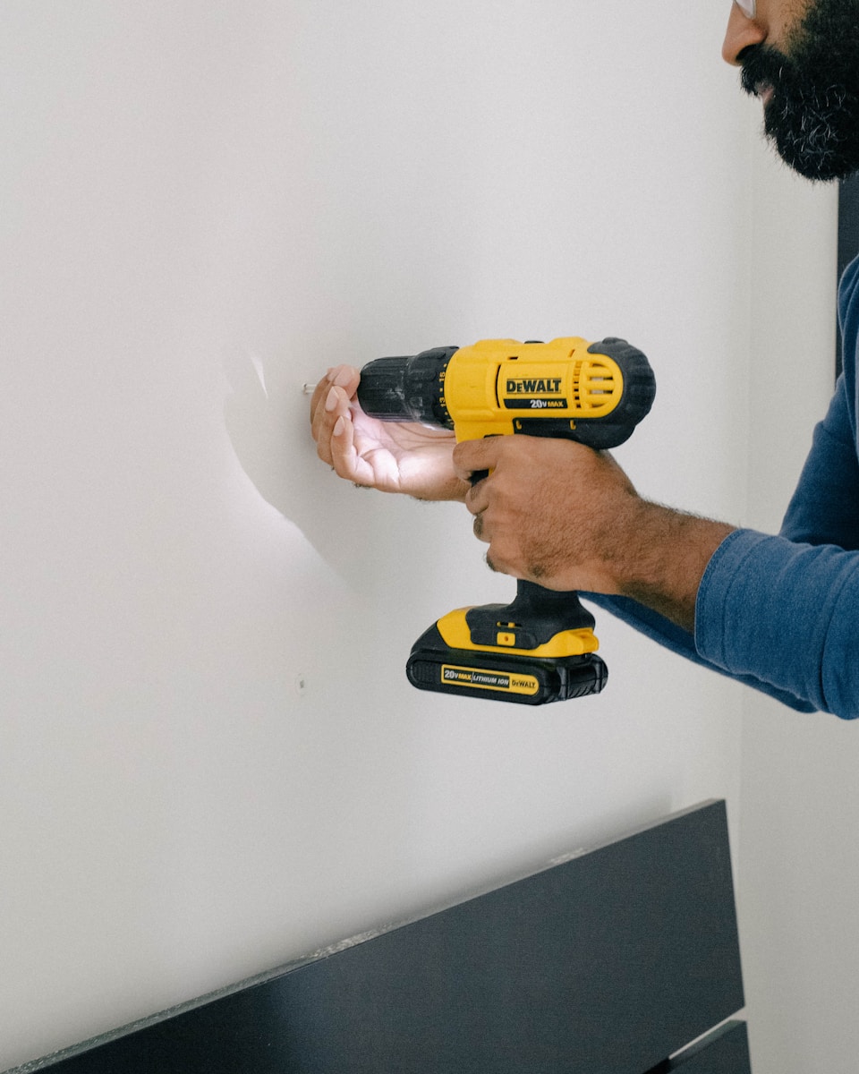 a man is holding a drill and a cordless drill performing homeowners home renovations